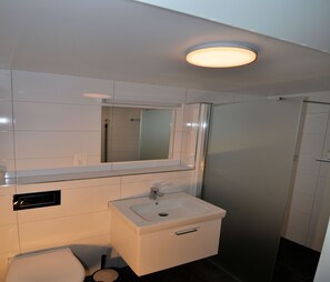 Ein modernes Badezimmer mit Waschbecken, Spiegel und Toilette in Weiß.
