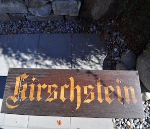 Ein hölzernes Schild mit der Schriftzug 'Kirschstein' in goldener Schrift.