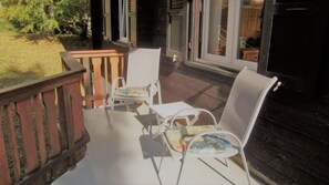 A wooden deck with a table and two chairs. - Lotus OG (Fiesch)
