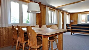 Un intérieur en bois avec une table et des chaises, de grandes fenêtres et un canapé.
