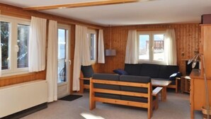 Une pièce confortable, aménagée comme un chalet, avec un intérieur en bois, un canapé, une table et une fenêtre avec des rideaux.