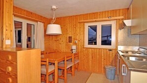 Une petite cabane en bois comprenant un coin repas, une kitchenette et une fenêtre offrant une belle vue.