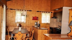 A wooden interior with a dining table and chairs, a kitchen area, and a small seating area. - Melchior (Fiesch)