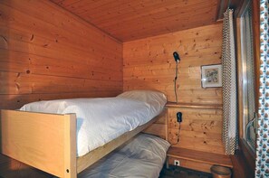 Una habitación de cabaña de madera con una litera y una mesita de noche pequeña.