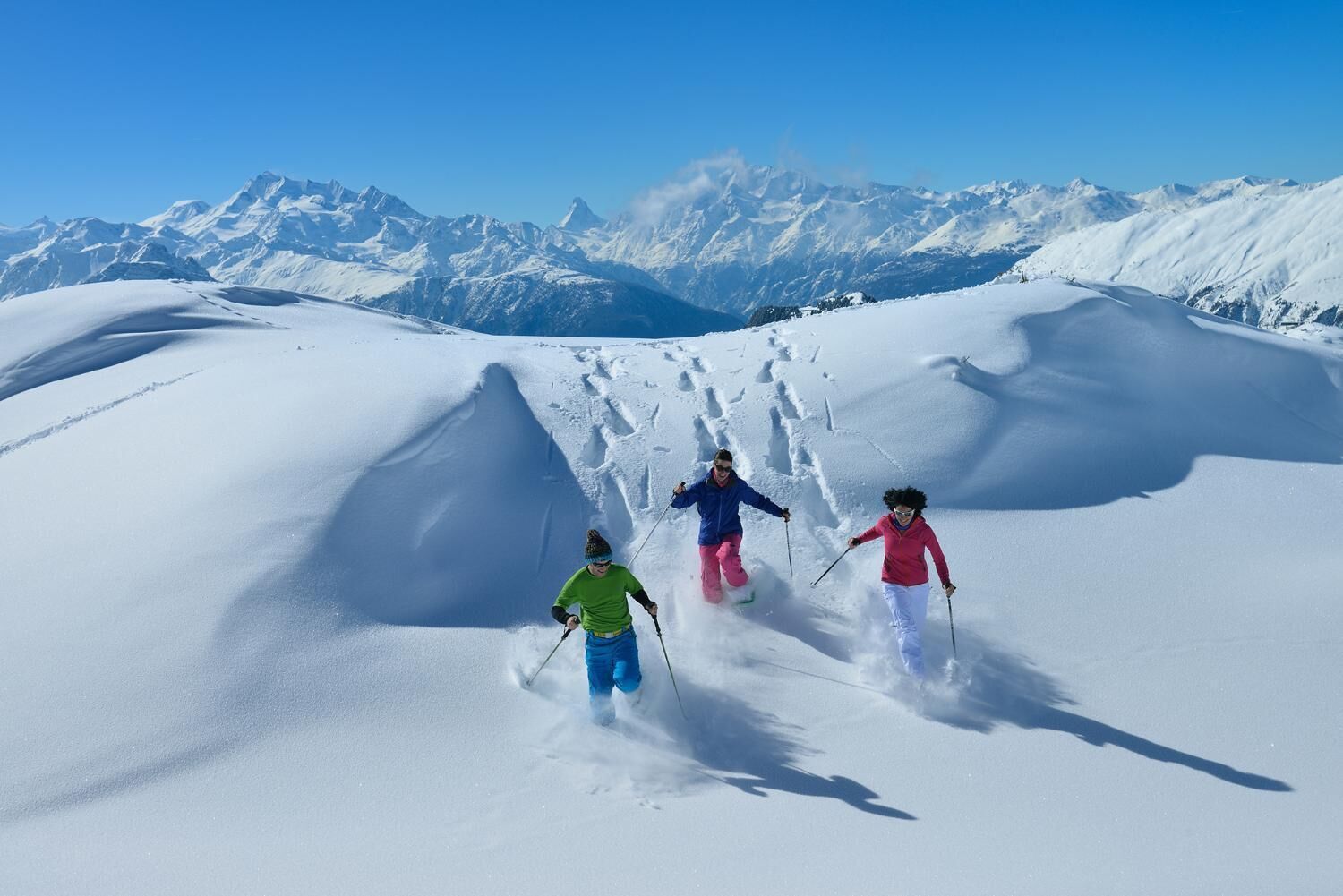 A snowy mountain landscape with skiers.