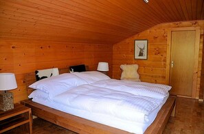 Un dormitorio de cabaña de madera con una cama, dos mesitas de noche y una puerta.