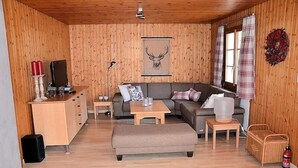 Un salon chaleureux avec un décor intérieur en bois, un canapé, une table basse, un téléviseur et une cheminée.