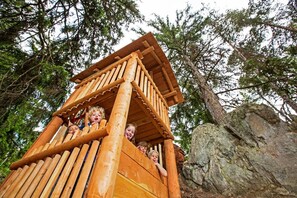 Una casita de juegos de madera con techo inclinado y una escalera.