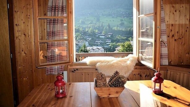 Une cabane en bois dotée d’une grande fenêtre donnant sur un village.