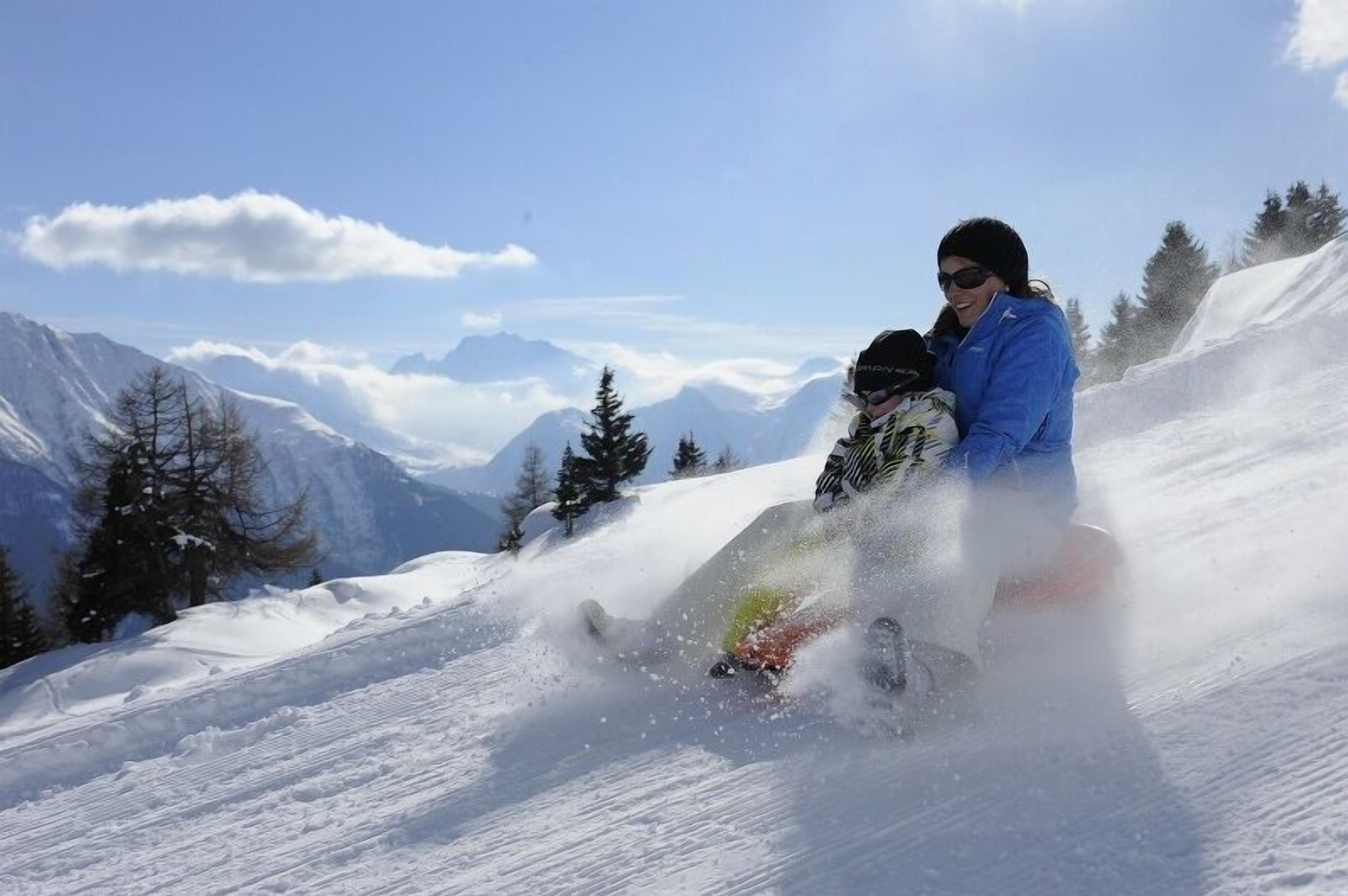 A snowy mountain slope with a person skiing.