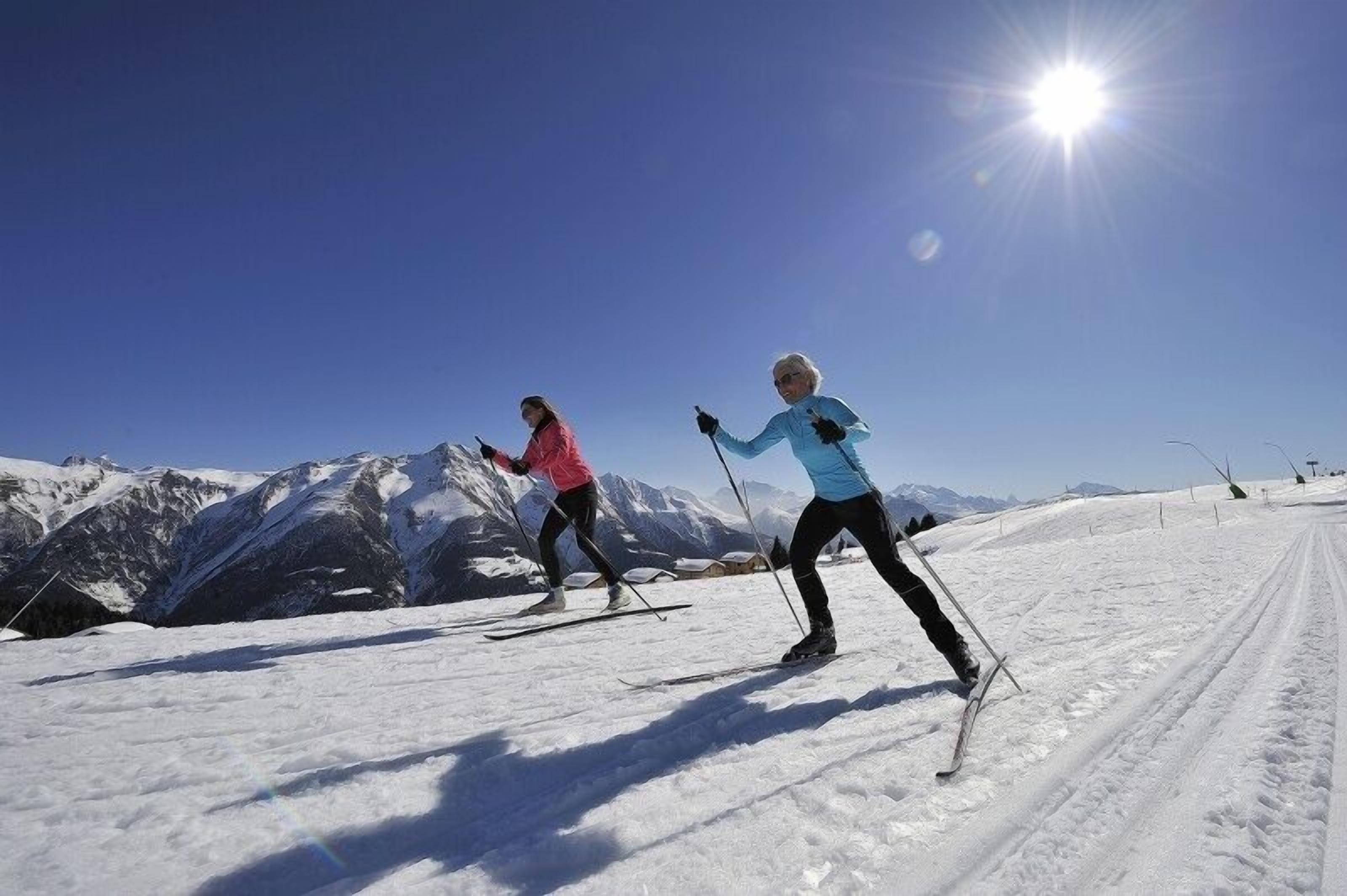 Two skiers on a snowy slope with mountains in the background.