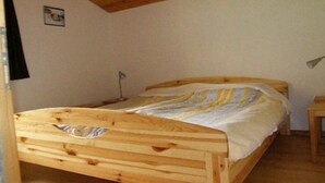 A wooden bed in a room with a sloped ceiling and a small bedside table.