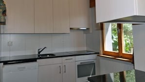 A kitchen with white cabinets, a black countertop, and a window with a view of greenery.