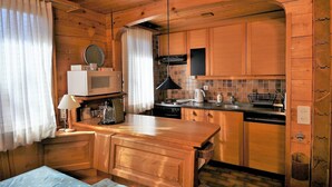 A compact kitchen with wooden cabinets, a microwave, a kettle, and a sink. - Uf der Egga 419 (Fiesch)