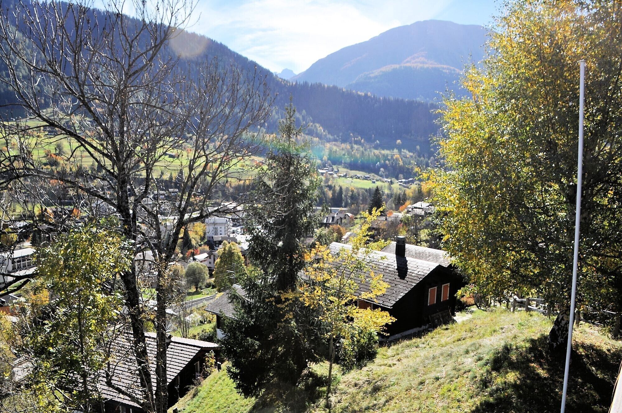 A rural village with traditional houses, surrounded by mountains and autumn foliage.