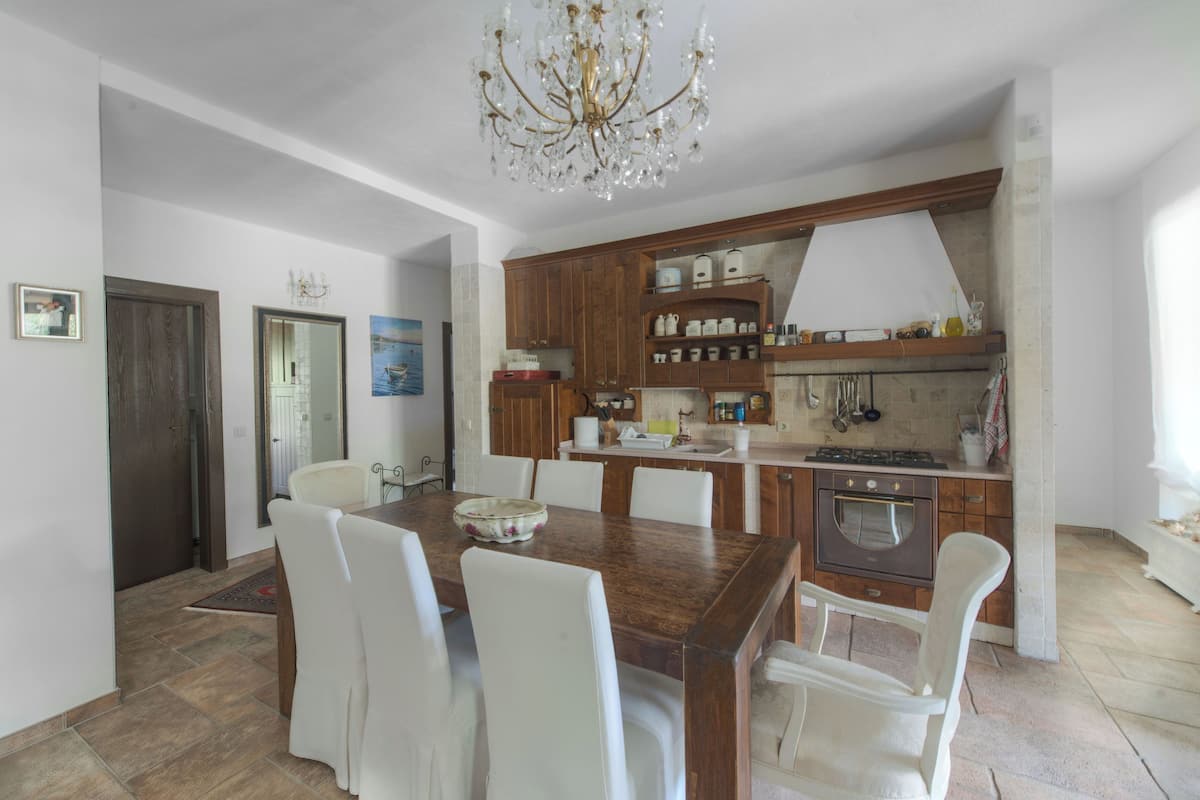 Una cocina moderna con armarios de madera, una mesa de comedor con sillas y una araña.