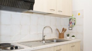 A kitchen with a double sink, a stove, and light-colored cabinets.