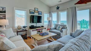 Ett vardagsrum med tv, soffa och utsikt över havet.
