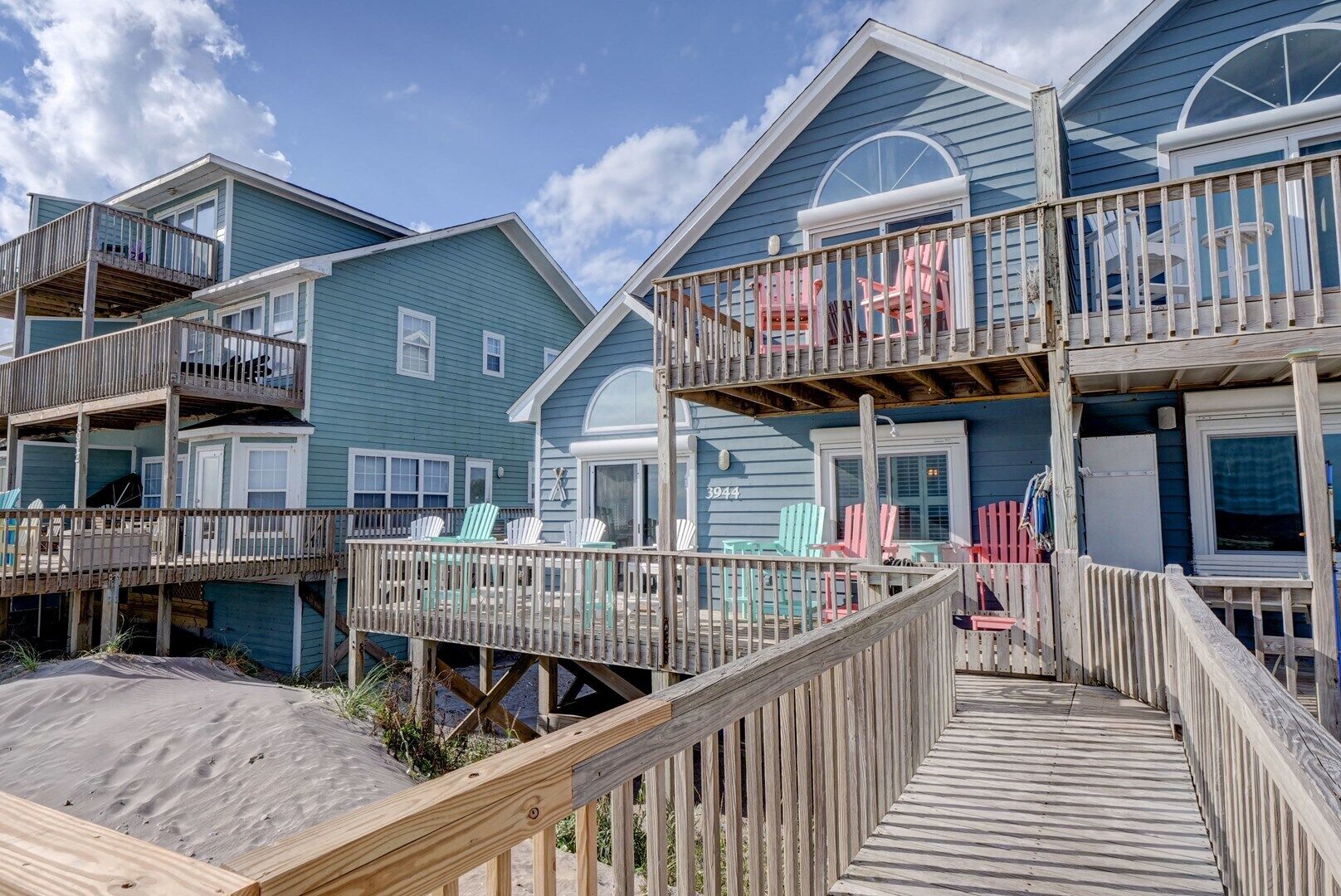 A beachfront property with multiple levels, each featuring a balcony with outdoor seating.