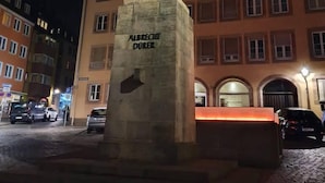 A statue on a pedestal with the inscription "ALBRECHT DÜRER" in a public square at night. - White Pearl Hostel 2 (Nuremberg)