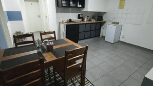 A compact kitchen with a dining area, featuring a small refrigerator, microwave, and cabinets. - White Pearl Hostel 2 (Nuremberg)