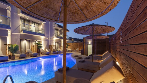 A modern hotel with a swimming pool, outdoor seating, and wooden deck areas. - Oasis Hotel Prasonisi (Rhodes)