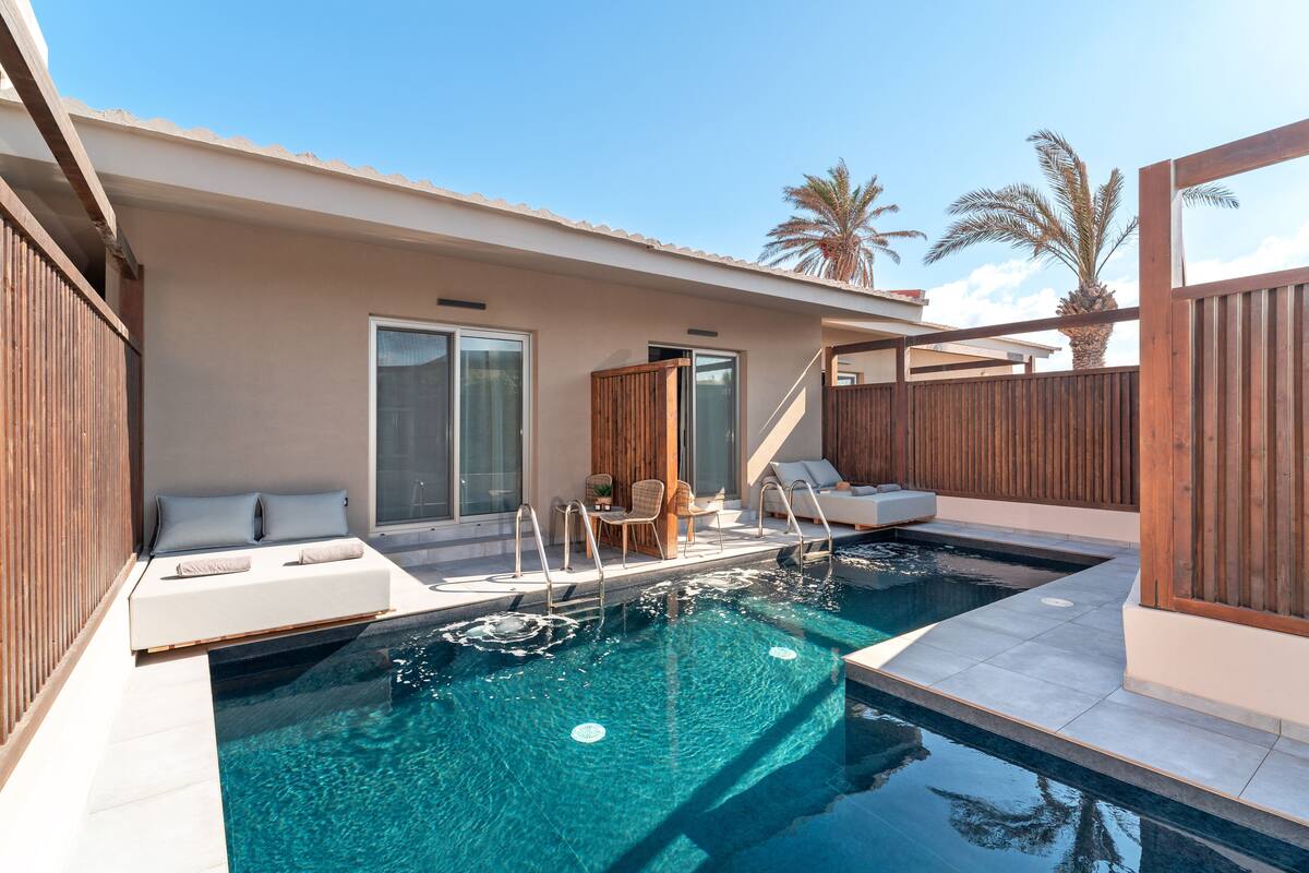 A modern outdoor pool area with a built-in seating area and a wooden fence.