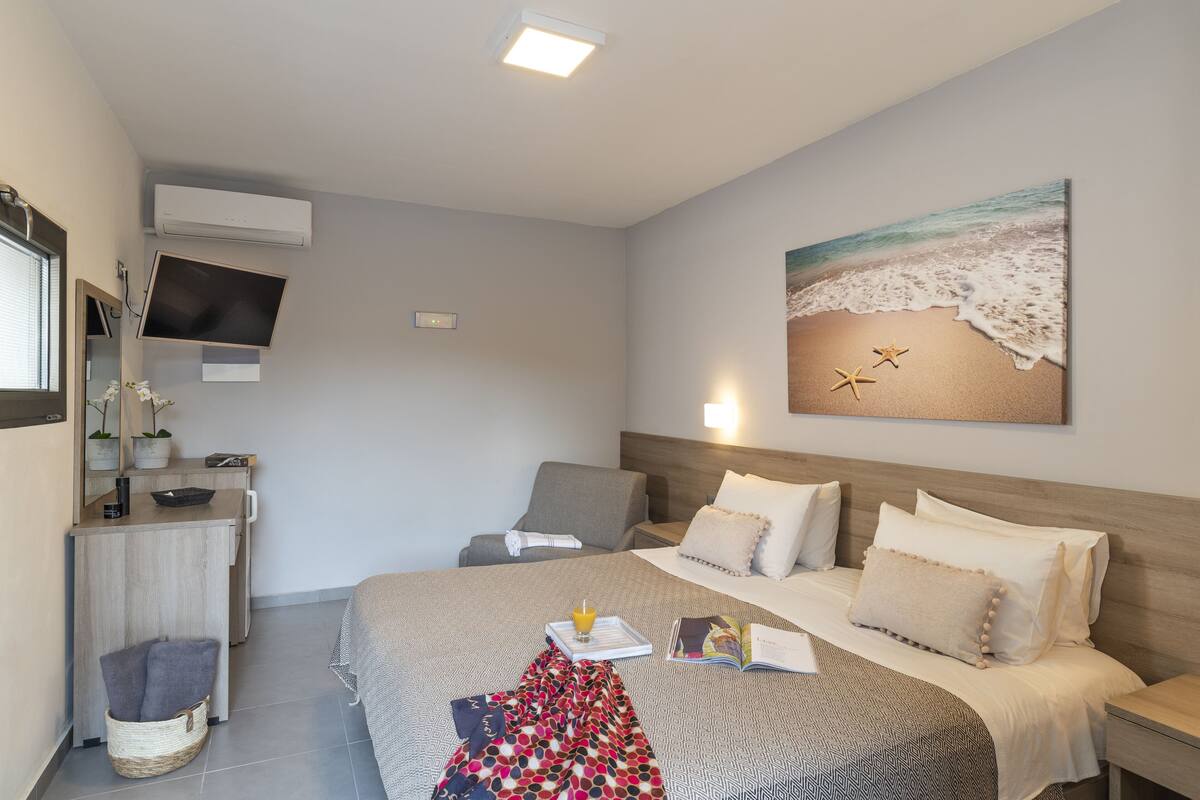 A hotel room with a bed, bedside table, and a wall-mounted TV.