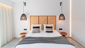 A modern bedroom with a large bed, two bedside tables, and a headboard with a woven pattern. - Oasis Hotel Prasonisi (Rhodes)