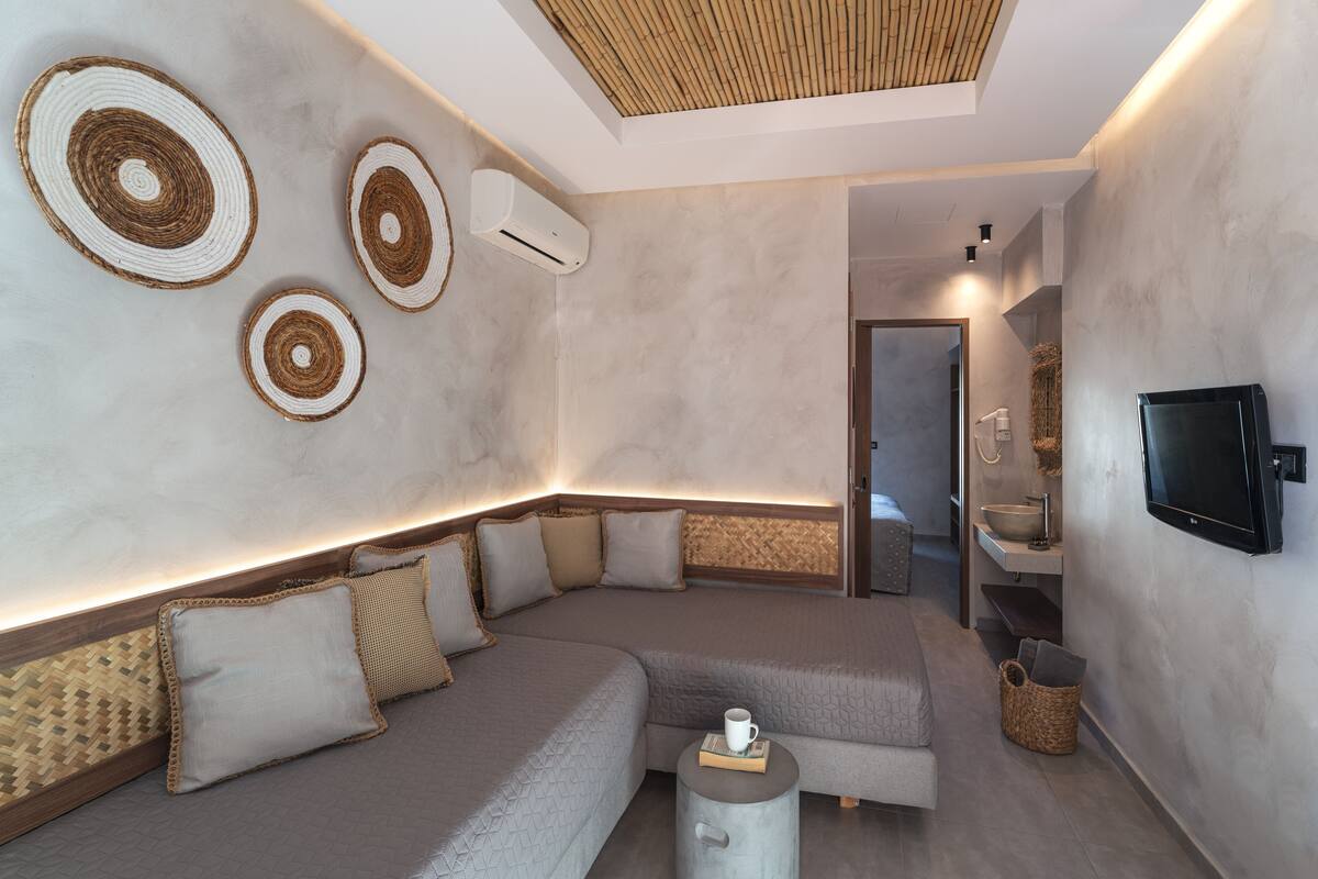 A modern room with a sectional sofa, a small table with a cup, and a TV mounted on the wall.