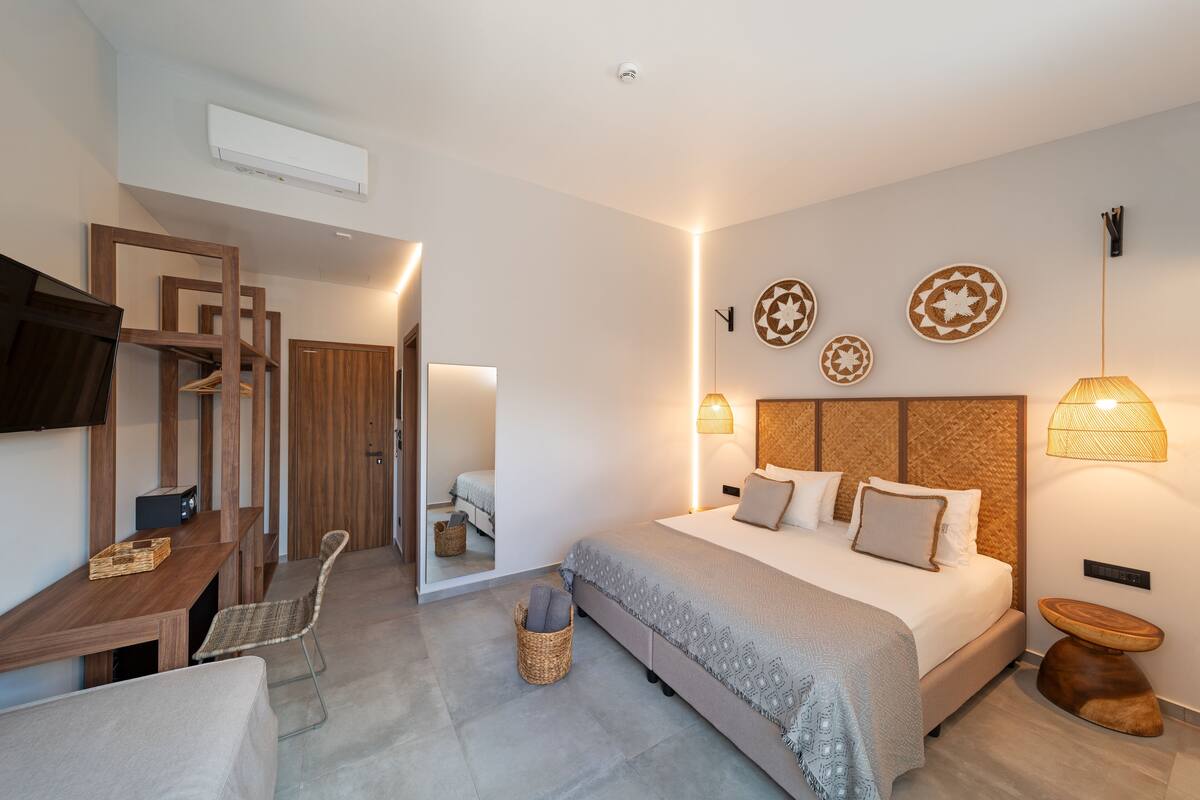 A modern bedroom with a large bed, bedside tables, a desk, and a TV.