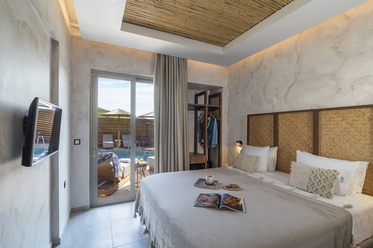 A hotel room with a large bed, a TV, a sliding glass door to a pool area, and a wardrobe.