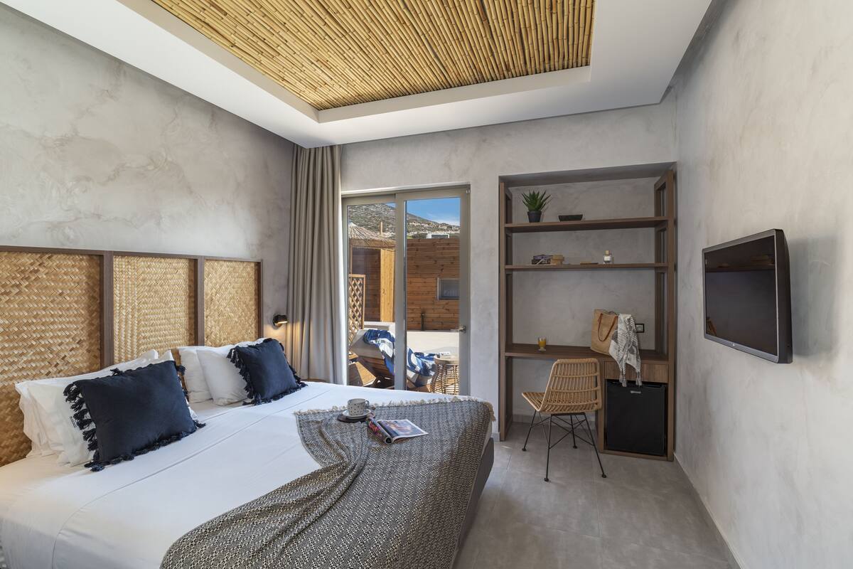 A modern bedroom with a large bed, a desk, and a TV.