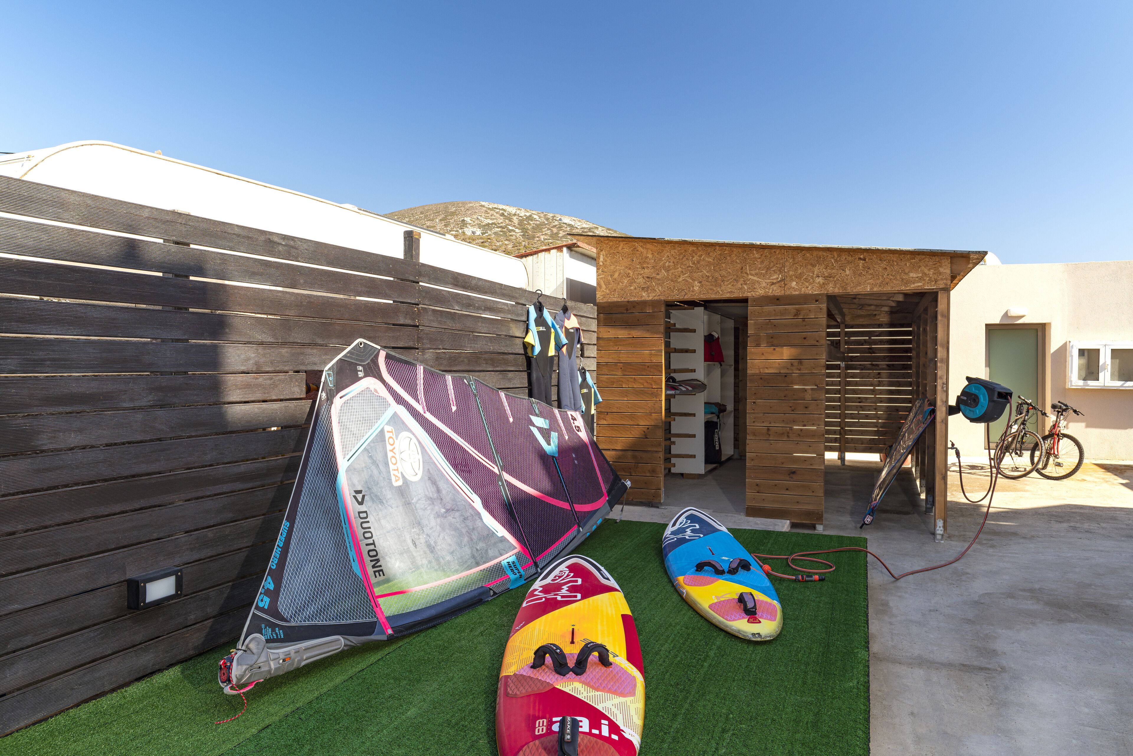 Un espacio al aire libre cubierto con tablas de surf y una bicicleta.
