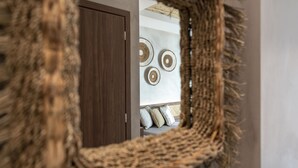 A mirror with a textured frame reflecting a room with a door and wall-mounted decor. - Oasis Hotel Prasonisi (Rhodes)
