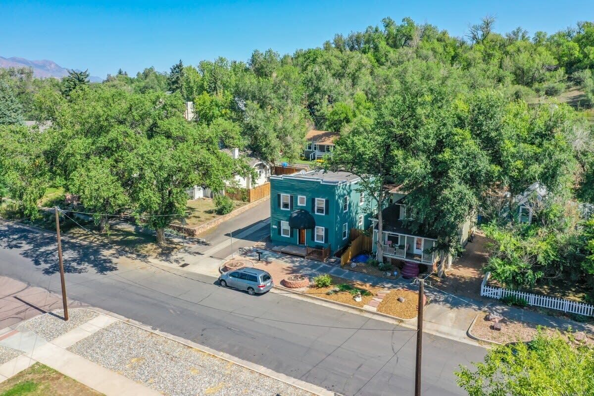 A two-story building with a green facade, a driveway, and a parked car.