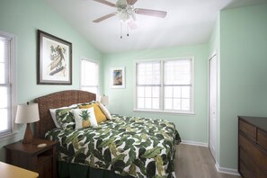 A bedroom with a bed, a nightstand, a lamp, a ceiling fan, and two windows. - Home away from home! (Key West)