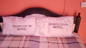 Een bed met een geruite sprei en twee kussens met de tekst 'NAIVASHA SILVERVIEW HOTEL'.