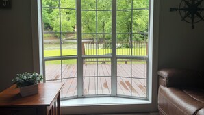 A room with a large bay window, a wooden deck, and a compass wall decoration.