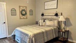 A bedroom with a bed, a nightstand, a lamp, and decorative wall art.