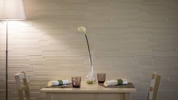 A dining table with a vase of white flowers, two glasses, and a candle.