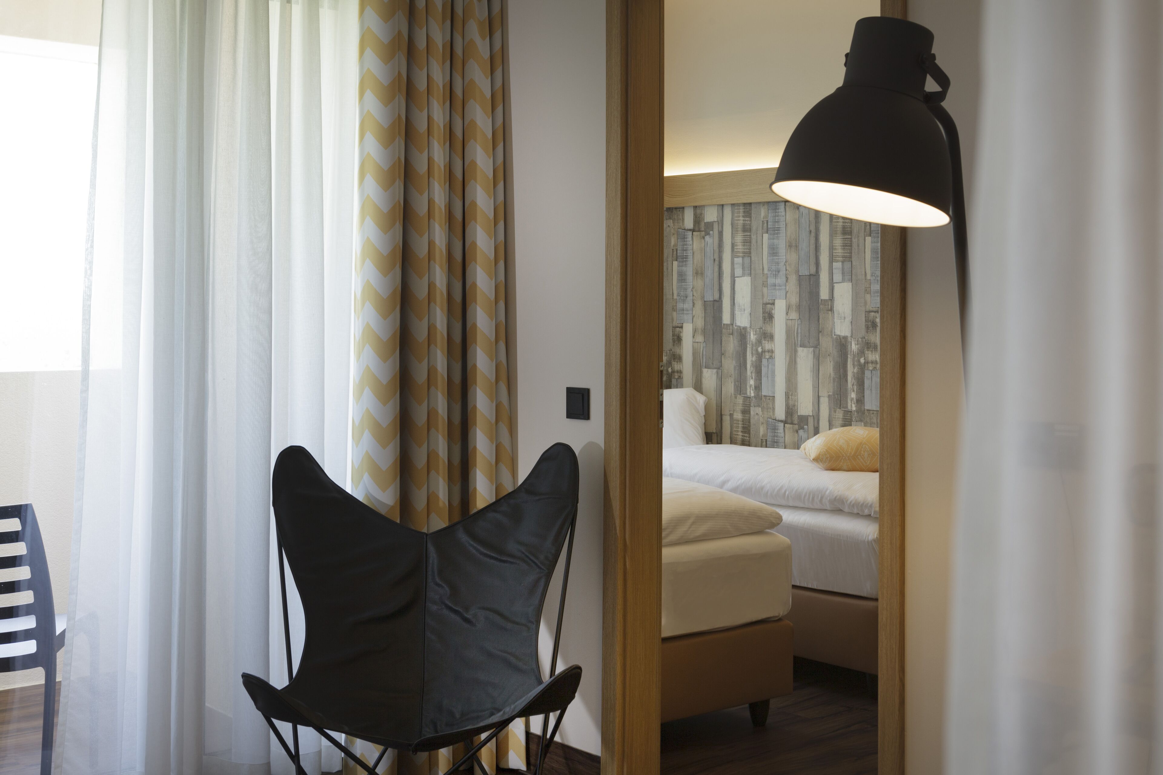 Ein Hotelzimmer mit einem Bett, einem Sessel und einer Lampe.
