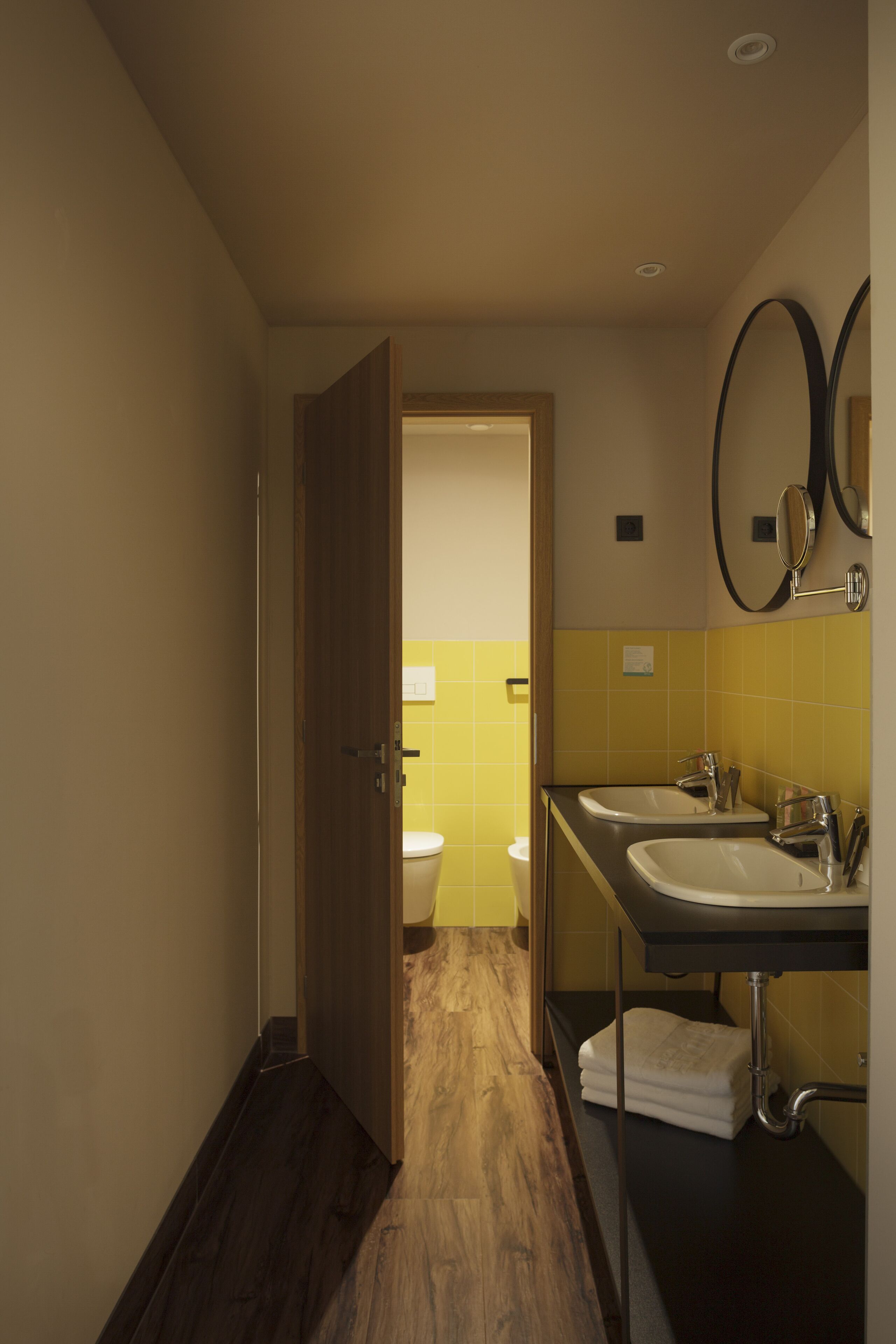 Un baño de hotel con dos lavamanos, un inodoro y un espejo.