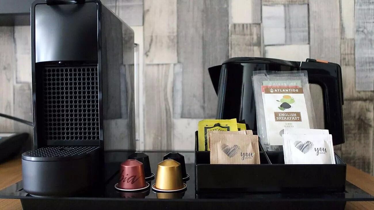 A coffee machine and a tray with coffee pods and bags of English Breakfast tea.