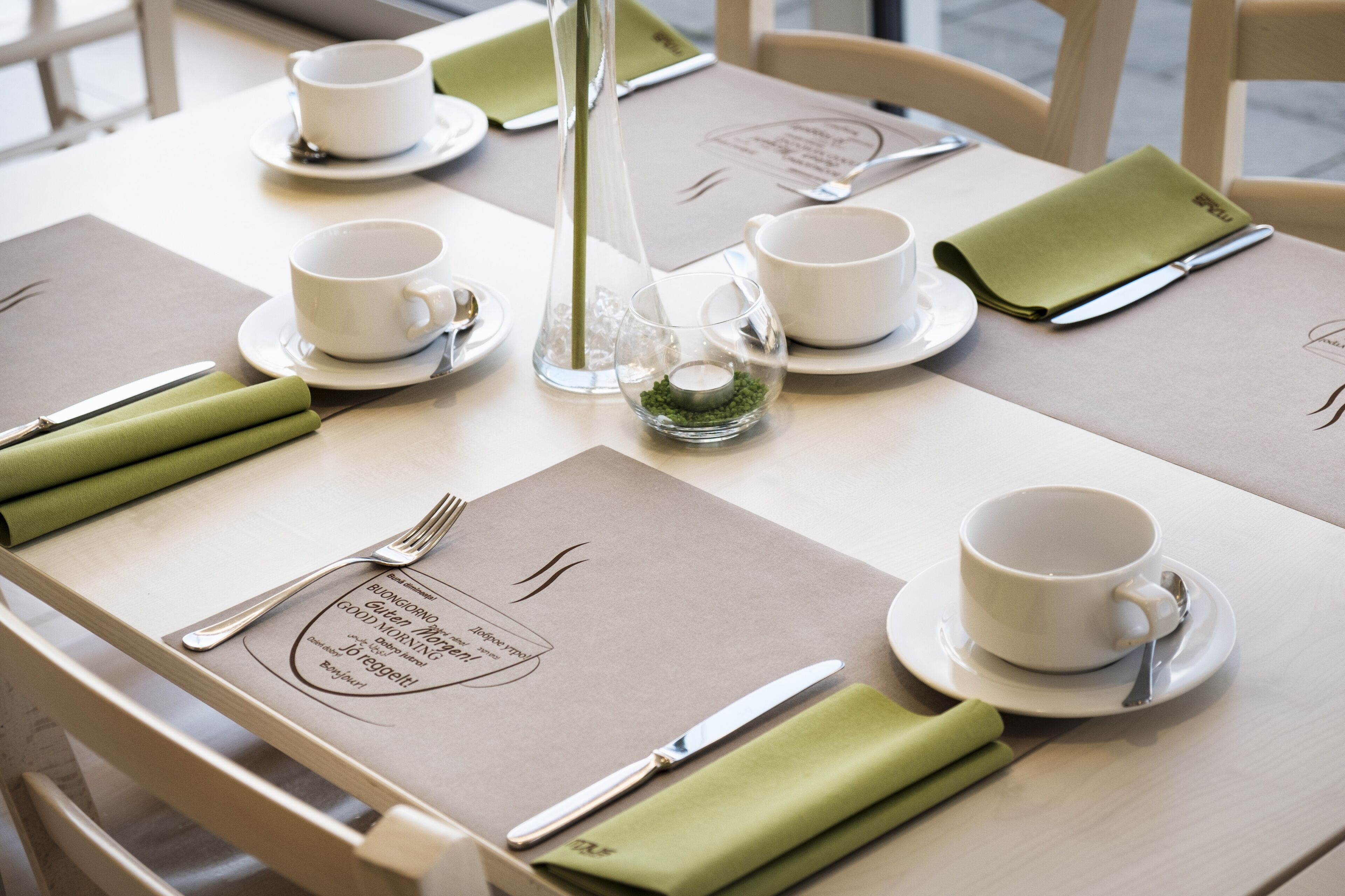 A neatly set dining table with a menu, cutlery, and a candle centerpiece.