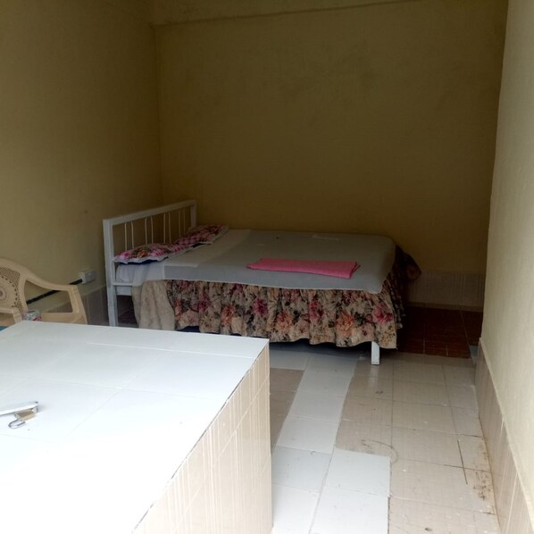A small, single-room apartment with a bed, a chair, and a table.