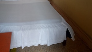 Un dormitorio con una cama, una ventana con cortinas y un cabecero de madera.