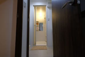 A narrow hallway leading to a bathroom with a toilet, sink, and a mirror.