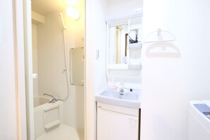 A bathroom with a shower, sink, and mirror.
