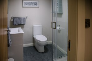 Ein modernes Badezimmer mit Waschbecken, Toilette und Dusche – alles in Weiß.